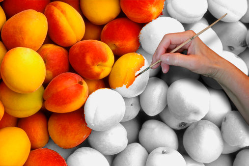 Close-up of a person's hand coloring on peaches